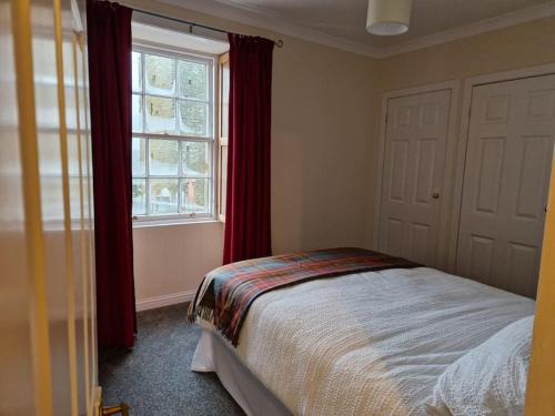 um quarto com uma cama com cortinas vermelhas e uma janela em The Old Post Office House em Perth