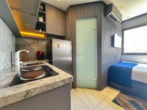 a kitchen with a sink and a refrigerator next to a bed at New Studios by VLV Stays in Salvador