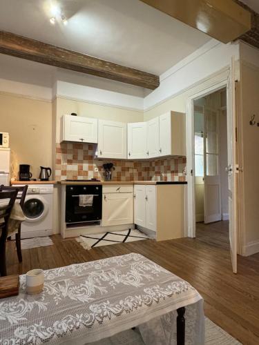 une cuisine avec des armoires blanches et une table dans une pièce dans l'établissement la campagne en ville, à Dieppe