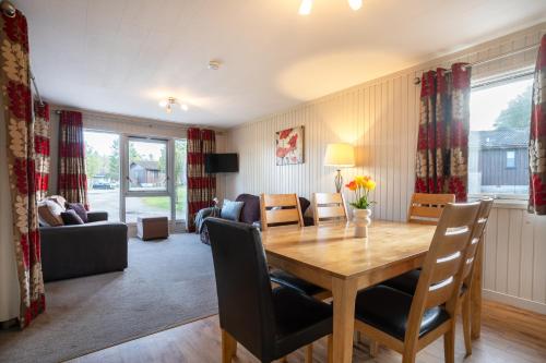 a living room with a wooden table and chairs at 3 Bedroom Lodge - Hunters Quay in Kirn