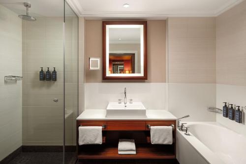 ein Badezimmer mit einem Waschbecken, einer Badewanne und einem Spiegel in der Unterkunft Sheraton Bratislava Hotel in Bratislava