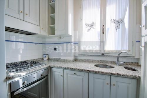 a kitchen with white cabinets and a sink and a stove at Mare appartamento ristrutturato e con posto auto in Castiglione della Pescaia