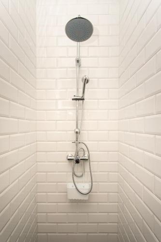 a shower in a bathroom with white tiles at Albergue Llanes Hostel in Llanes