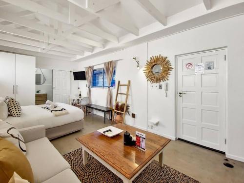 een witte woonkamer met een bank en een tafel bij Unique Studio Close to Promenade in Kaapstad