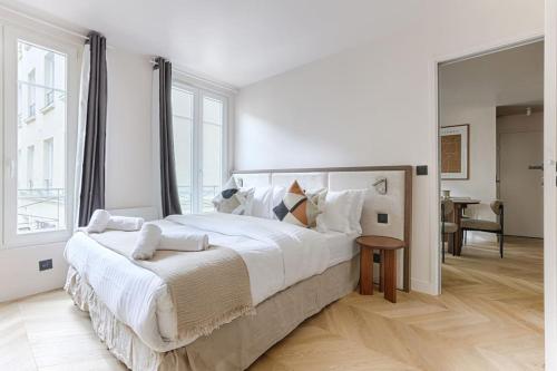 une chambre blanche avec un grand lit et une table dans l'établissement MyKeypers - Luxury & Design Flat 1BR/4P- Bastille, à Paris