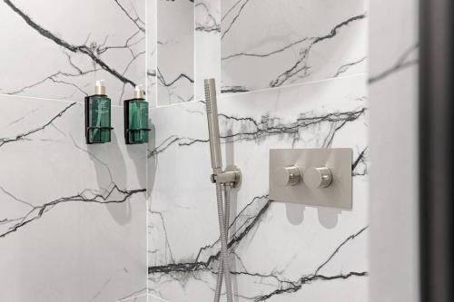 La salle de bains est pourvue d'une douche et de murs en marbre. dans l'établissement MyKeypers - Luxury & Design Flat 1BR/4P- Bastille, à Paris