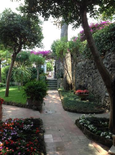 einen Garten mit Blumen und einer Steinmauer in der Unterkunft Villa Melpomene in Ischia