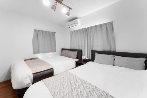 a hotel room with two beds and a window at City House 暁 -akatsuki- in Osaka