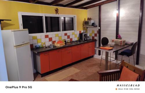 a kitchen with red cabinets and a white refrigerator at Appartement charmant à Rivière-Pilote - 30 m² avec terrasse in Rivière-Pilote