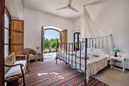 um quarto com uma cama de dossel e uma cadeira em Casa da Terra Branca em Vila Nova de Cacela