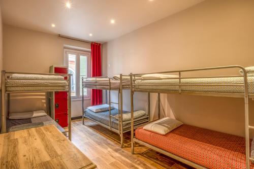 a room with three bunk beds and a table at Villa Saint Exupery Beach Hostel in Nice