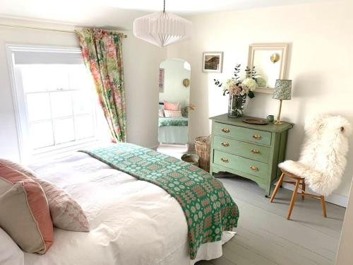a bedroom with a bed and a dresser and a chair at The Yellow cottage on the hill. in Framlingham