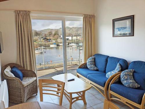 a living room with a blue couch and a large window at Harbour Haven: Spectacular Views in Porthmadog