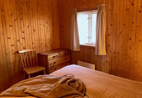 a bedroom with a bed and a window and a chair at Nusfjord Ocean View Rorbu 19 in Ramberg
