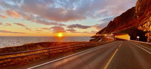 a road leading to a tunnel in the ocean at sunset at Nusfjord Ocean View Rorbu 19 in Ramberg