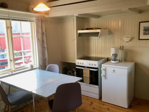 a small kitchen with a table and a white refrigerator at Nusfjord Ocean View Rorbu 19 in Ramberg