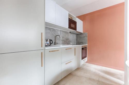 une cuisine blanche avec des armoires et des appareils blancs dans l'établissement MyKeypers - Chic & Elegant Flat 2BR/6P- République, à Paris
