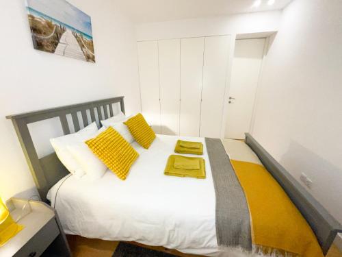- une chambre avec un grand lit blanc et des oreillers jaunes dans l'établissement Lisbon Charming Santos Apartment w/ Patio, à Lisbonne