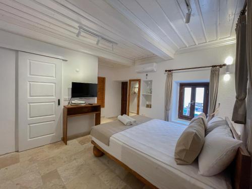 una camera con un grande letto e una televisione di NİYAMA MARİNA Butik Hotel a Çeşme