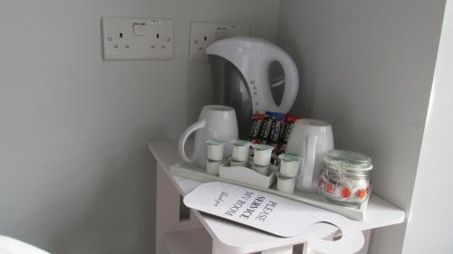 ein Regal mit Tassen und einem Spiegel in einem Zimmer in der Unterkunft Rooms at The Ritz Complex in Desborough