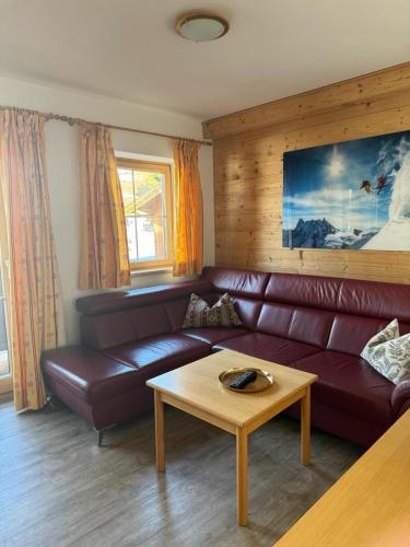 a living room with a brown leather couch and a coffee table at Weinzeit Chalet in Königsleiten
