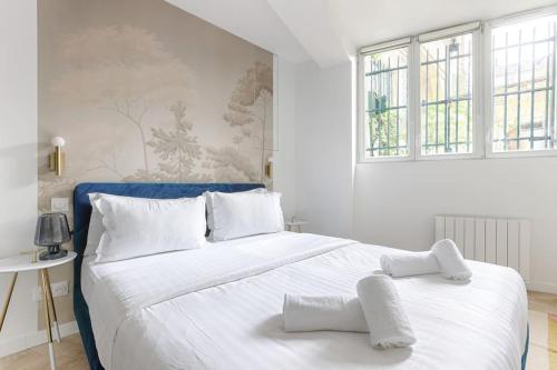 - une chambre avec un grand lit blanc et des oreillers blancs dans l'établissement MyKeypers - Chic & Cozy Flat 4P - République, à Paris