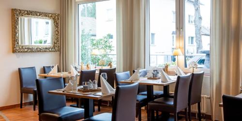 a dining room with tables and chairs and a mirror at Hotel Hangelar in Sankt Augustin