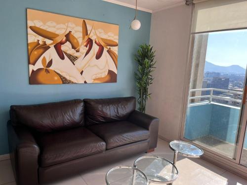ein Wohnzimmer mit einem braunen Ledersofa und einem Gemälde in der Unterkunft Gran Santiago Apart in Santiago