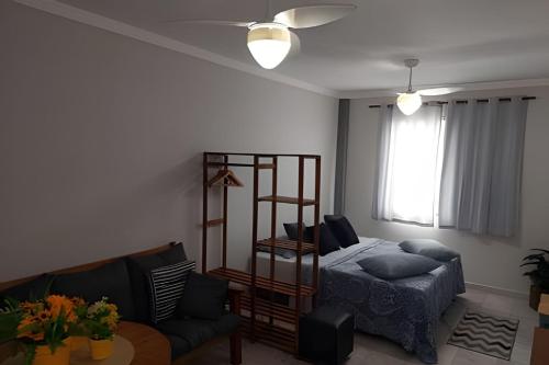 una sala de estar con una cama y un sofá en Em frente ao quiosque Ocian na praia, pé na areia, en Praia Grande