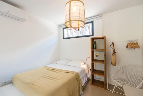 een slaapkamer met een bed, een raam en een kroonluchter bij Le LilaRosa, Terrasse, Clim, Pkg, Centre Ville in Montpellier