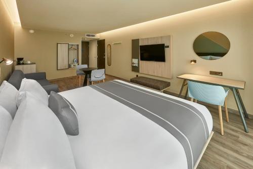 a hotel room with a large bed and a living room at City Express Plus by Marriott Ensenada in Ensenada