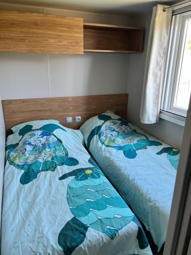 a bedroom with a bed with a fish themed bedspread at Mobil home neuf 6 p à Hyères dans camping 4 étoiles Les Pins Maritimes in Hyères