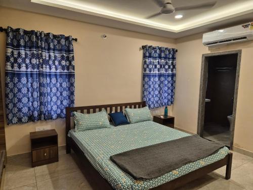 a bedroom with a bed with blue curtains at Swayamkrushi 2nd Floor in Hyderabad