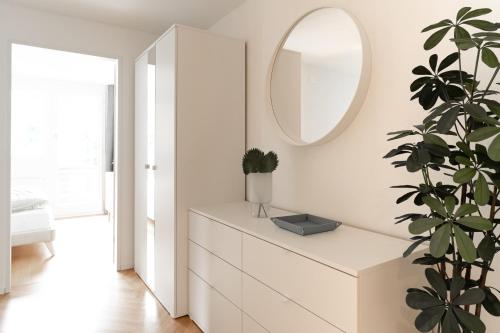 - une commode blanche avec un miroir et une plante dans l'établissement Apartment mit 3 Schlafzimmern, à Engelberg