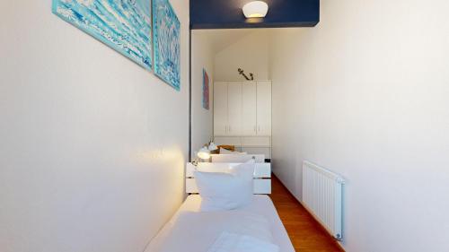 ビンツにあるVilla Strandidyllの白いベッドと青い絵画が備わる小さなお部屋です。