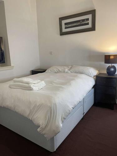 a bedroom with a bed with white sheets and a lamp at Spacious flat next to central station in Glasgow