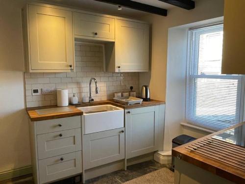 a kitchen with white cabinets and a sink at Atlantic Cottage Port Isaac 2 bedroom with parking in Port Isaac