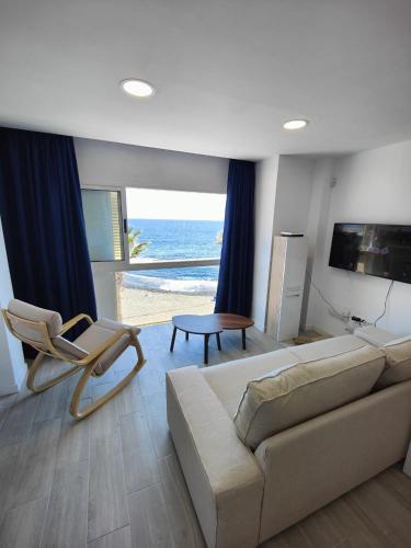 a living room with a couch and chairs and the ocean at Vacacional Sunbeach Candelaria in Candelaria