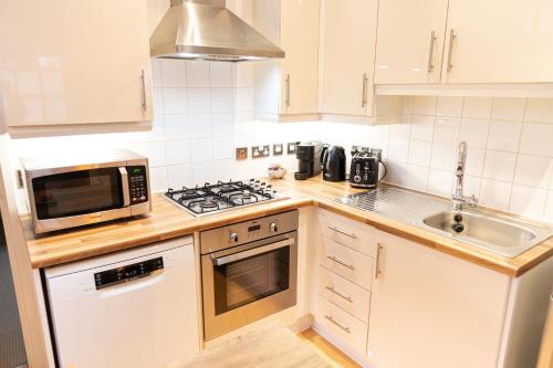 a kitchen with a stove and a microwave and a sink at Vibrant Two Bedroom House near Canary Wharf in London