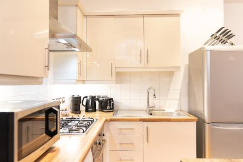 a white kitchen with a sink and a refrigerator at Vibrant Two Bedroom House near Canary Wharf in London