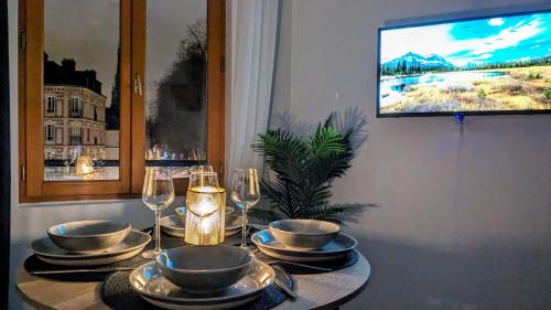 - une table avec des assiettes, des verres à vin et une télévision dans l'établissement La Flèche Saint Vivien: Hypercentre & Cathédrale, à Rouen