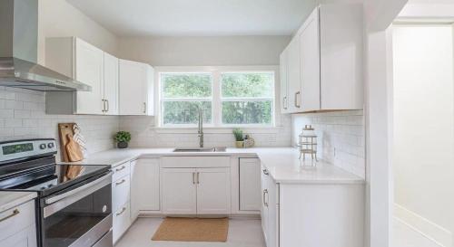 una cucina bianca con mobili bianchi e una finestra di Modern Chateau Remodeled Home Close to Downtown a Mobile