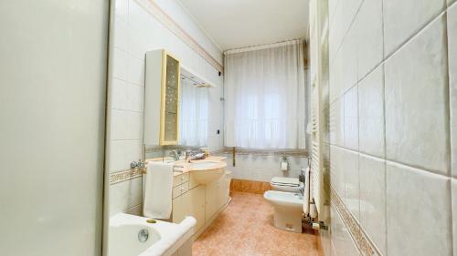 łazienka z 2 umywalkami, toaletą i lustrem w obiekcie Appartamento al Mare w mieście Chioggia