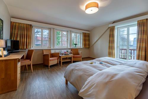 Habitación de hotel con cama, escritorio y ventanas en Seehotel Zarrentin en Zarrentin
