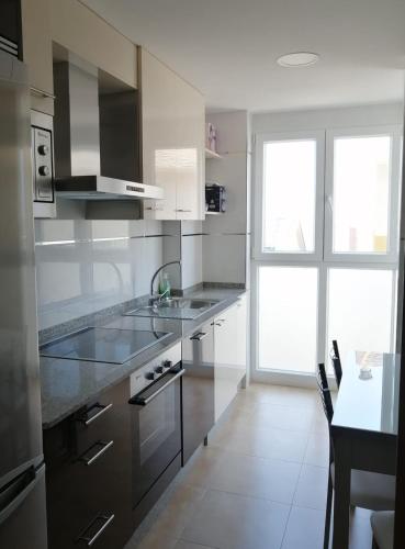 a kitchen with stainless steel appliances and a large window at Apartamentos Rompeolas in Burela de Cabo