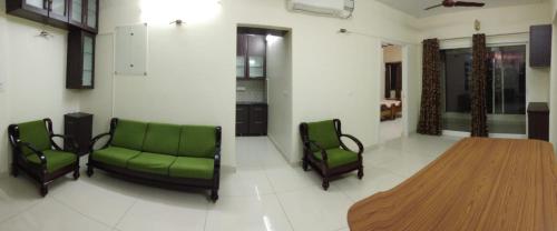 uma sala de estar com cadeiras verdes e uma mesa de madeira em Bed and Brew em Chennai