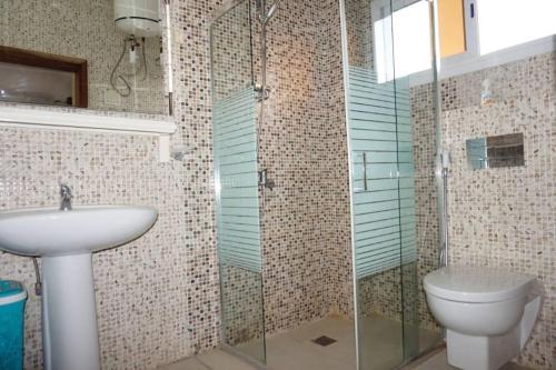 a bathroom with a toilet and a glass shower at Appartement F3 Almadies vue/mer accès+ Dakar in Dakar
