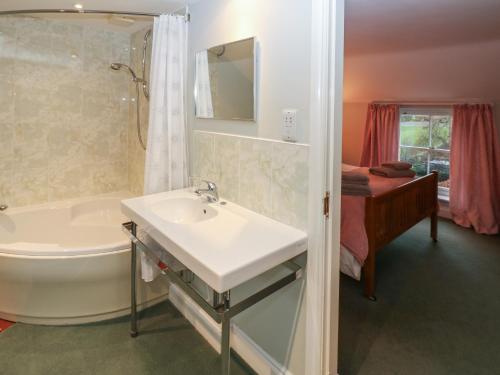 a bathroom with a sink and a tub and a shower at Garden Cottage in Penrith