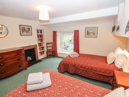 a bedroom with two beds and a fireplace at Garden Cottage in Penrith
