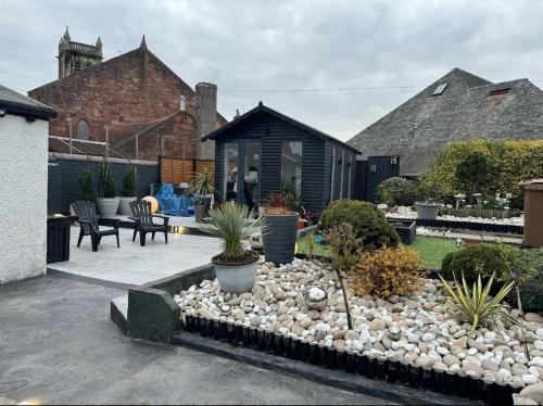 a garden with rocks and plants in front of a house at Royal Troon Open Championship 24 in Prestwick